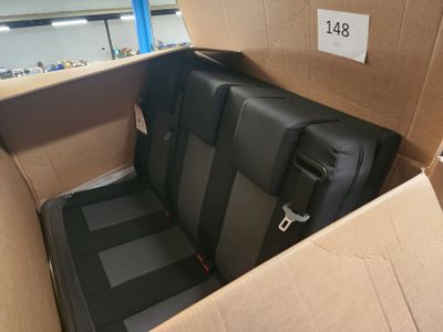 a black seat in a cardboard box with a tag on it