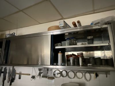 une étagère métallique avec des casseroles et des poêles dans une cuisine