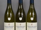 three bottles of white wine are lined up on a table