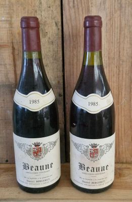 two bottles of wine sitting on a shelf next to each other