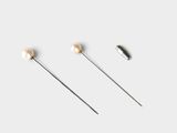 three pairs of pins with pearls on them on a white surface