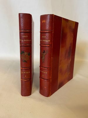 two red books sitting on top of each other on a white surface