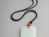 pendentif en jade blanc orné d'une perle rouge, monté sur un cordon noir