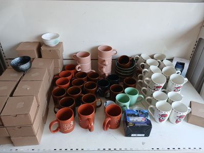 de nombreuses tasses et mugs posés sur une étagère à côté d'une boîte
