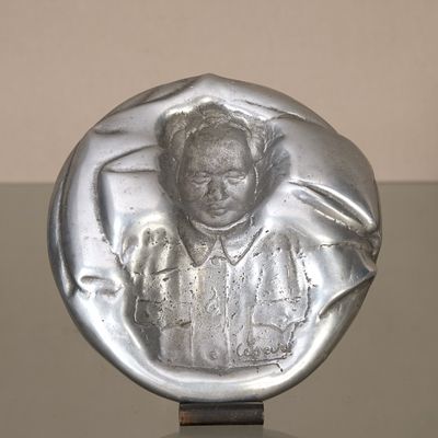 une photo d'une sculpture en argent représentant une femme, posée sur une table