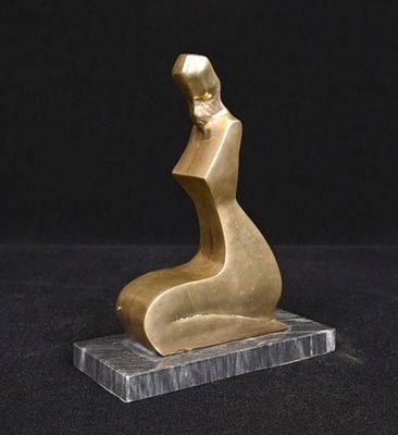 une statue en or représentant une femme assise sur un socle en marbre