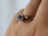 a woman ' s hand holding a ring with a black and white diamond
