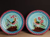 two plates with birds painted on them sitting on a table