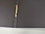 a black binder with a gold handle on top of a desk