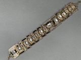 un gros plan d'un bracelet en or et diamants posé sur une surface grise