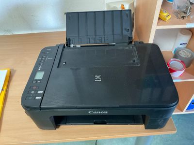 une imprimante posée sur un bureau, à côté d'une bibliothèque