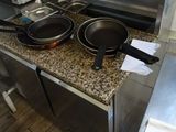 des casseroles et des poêles sont posées sur un plan de travail dans une cuisine