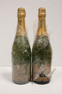 two bottles of champagne wrapped in plastic wrap on a white surface