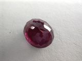 a close up of a red stone on a white surface