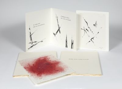 trois livres maculés d'encre rouge, posés sur une surface blanche