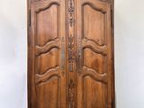 an old wooden armoire with a carved top and two doors