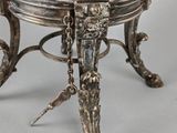 an antique silver plate with a bird on it on a stand