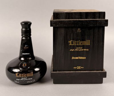 la bouteille se trouve à côté d'une boîte en bois avec un couvercle noir