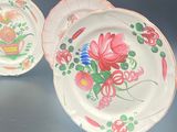 two plates with flowers painted on them sitting on a table