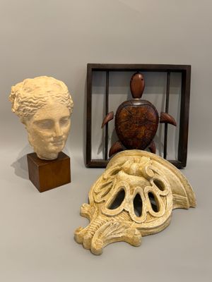 trois œuvres d'art sont exposées dans une vitrine posée sur une surface blanche