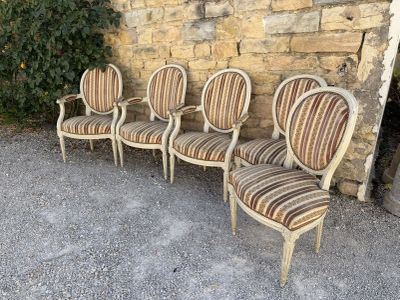 four chairs are lined up against a stone wall in front of a brick wall