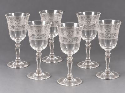 six verres à pied en verre gravé et quatre verres à vin posés sur une table