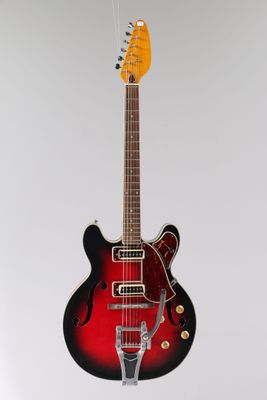 a red and black electric guitar sitting on top of a white surface