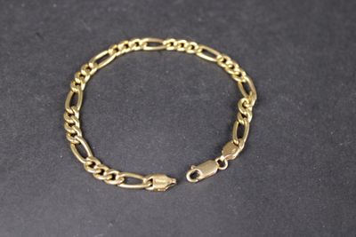 gros plan d'un bracelet en chaîne en or sur une surface noire