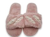 des chaussons roses ornés de perles et de nœuds, sur fond blanc