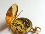 a gold pocket watch sitting on a white surface