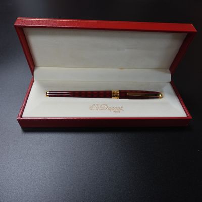 une boîte rouge contenant un stylo, posée sur une table