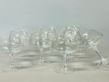 six clear wine glasses are lined up in a row on a white surface
