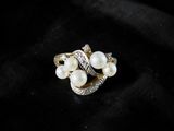 a close up of a pearl and diamond ring on a black cloth