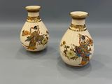 pair of chinese vases with figures on them sitting on a table