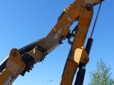 a backhoe of a yellow excavator that is on the side of the road