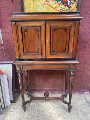 une armoire en bois sur le dessus de laquelle est accrochée une peinture