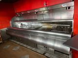une grande cuisine professionnelle équipée d'appareils électroménagers en inox et aux murs rouges