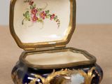 a blue and gold box with flowers on it on a table