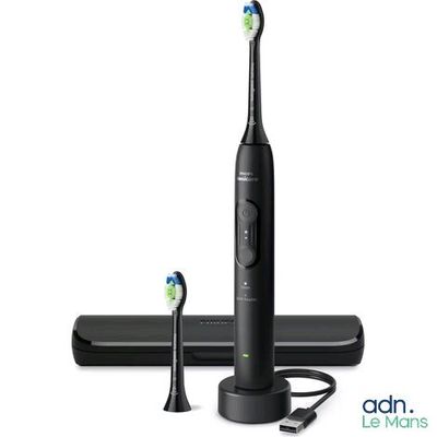 une photo d'une brosse à dents électrique noire posée à côté d'un chargeur
