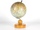 un petit globe posé sur un socle en bois, lui-même posé sur une surface blanche