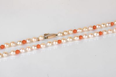 un collier de perles orange et blanches avec un fermoir en or