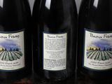 three bottles of wine are lined up on a wooden table