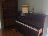 a piano in the corner of a room with a bookcase