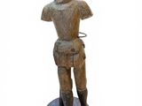 figurine en bois représentant un homme coiffé d'une capuche et les mains sur les hanches