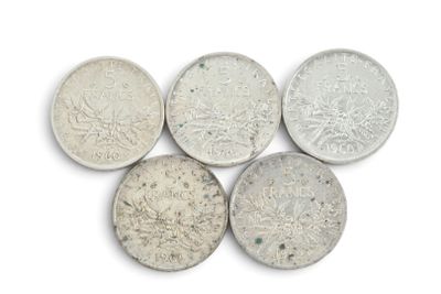 six types différents de pièces d'argent posées sur une surface blanche
