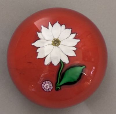 a red ball with a white flower and a green leaf on it