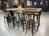 Des tables et des tabourets sont disposés dans une pièce aux murs noirs.