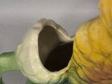 a green and yellow vase sitting on a white table