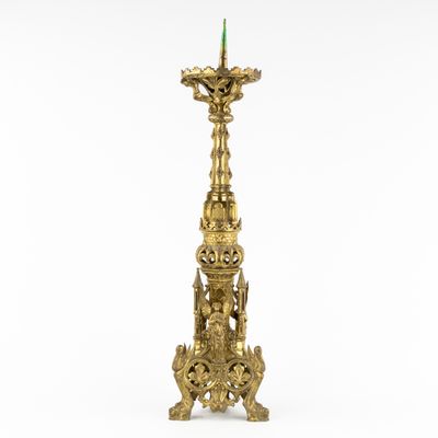 an antique brass candle holder with a green candle on top