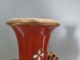 a red vase with gold decoration on it sitting on a table